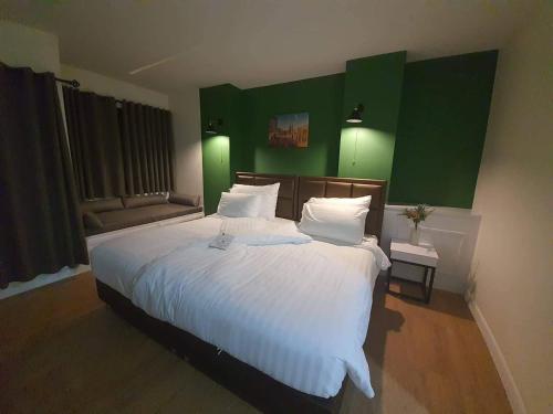 a bedroom with a large white bed with green walls at โรงแรมต้นเงิน in Khon Kaen