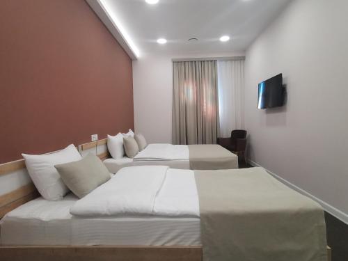 a hotel room with two beds and a television at Bonjour Boutique Hotel Yerevan in Yerevan