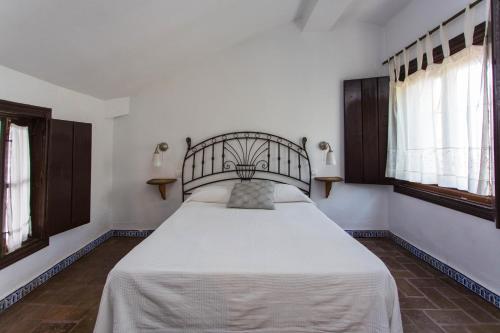 a large bed in a room with windows at Casa del siglo XVII in Seville