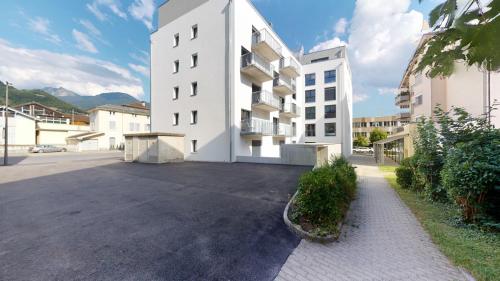 an empty parking lot in front of a white building at Nonanteneuf Appart-hôtel - Aigle in Aigle