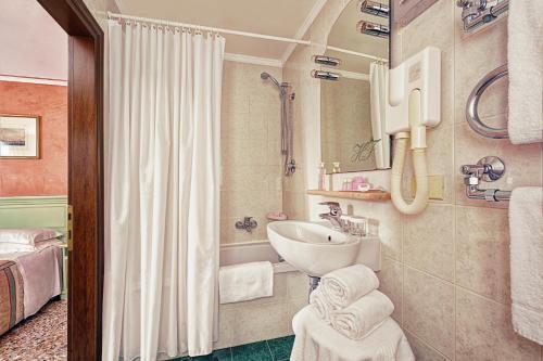 a bathroom with a sink and a bath tub at Hotel Firenze in Venice