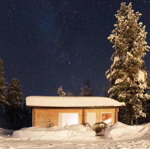 a small cabin in the snow at night at Mökki - The White Blue Wilderness Lodge in Inari