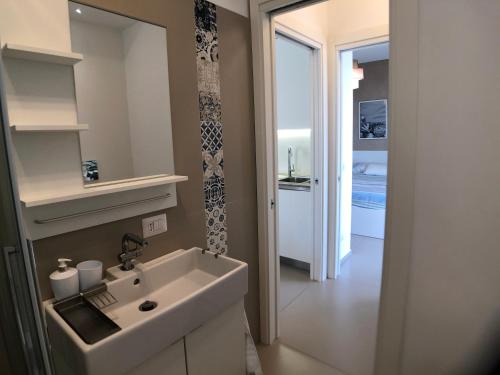 uma casa de banho com um lavatório branco e um quarto em Vista Mare Apartment con parcheggio privato em Marina di Ragusa