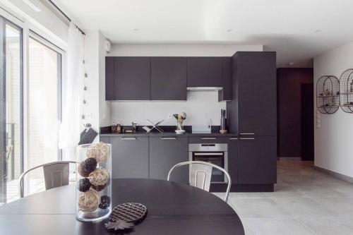 une cuisine avec une table et des chaises et une cuisine avec des placards sombres dans l'établissement Appartement 4 étoiles bord de plage et parking Chez Suzette, à Saint-Malo