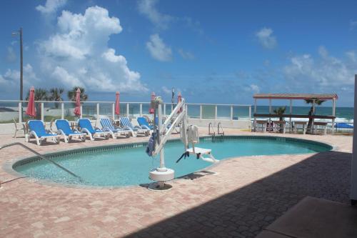 - une piscine avec des chaises et un toboggan dans l'établissement Cove Motel Oceanfront, à Daytona Beach
