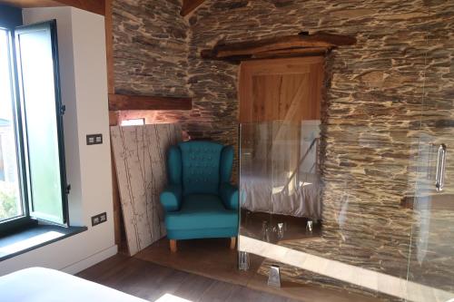 een blauwe stoel in een kamer met een stenen muur bij A Palleira de Lola in Lugo