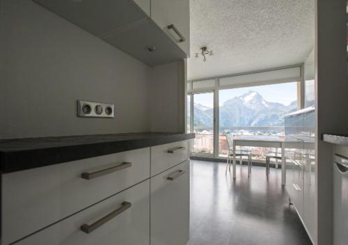 une cuisine avec des placards blancs et une vue sur la montagne. dans l'établissement Appartement 4 personnes (+1) LES 2 ALPES, à Mont-de-Lans