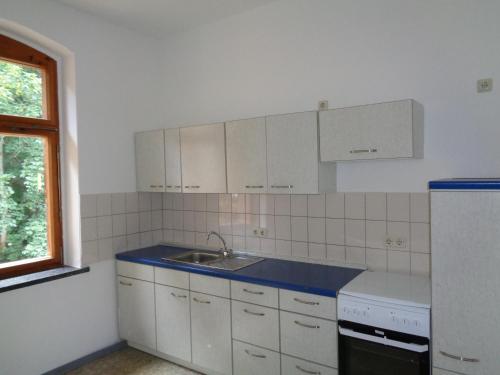 uma cozinha com armários brancos, um lavatório e uma janela em Pension Bahnmeister em Probstzella