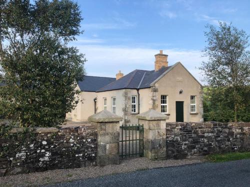 a white house behind a stone fence with a gate at Grannan School, Trillick, Fermanagh and Omagh, Tyrone in Trillick