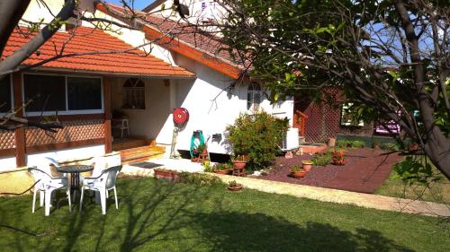 a house with a table and chairs in the yard at Jordan Valley one room apartment in Menaẖemya