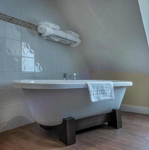a white bath tub in a bathroom with a towel at The Talbot Hotel, Oundle , Near Peterborough - The Coaching Inn Group in Oundle