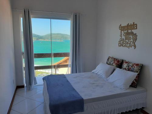 a bedroom with a bed with a view of the ocean at Bela Vista Flats in Arraial do Cabo