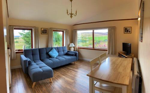 a living room with a blue couch and a table at Easter Corrie Cottages in Ballindalloch