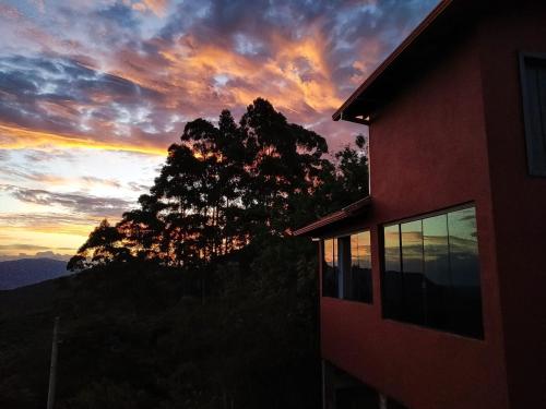 widok na zachód słońca na budynek i drzewo w obiekcie Chalé Panorâmico w mieście Ouro Preto