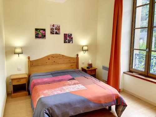 a bedroom with a bed and two tables and a window at Appartement 202 Résidence du Grand Hotel Aulus-les-Bains in Aulus-les-Bains