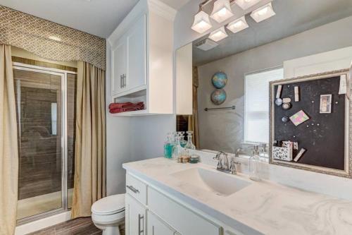 a white bathroom with a sink and a toilet at Vals Eclectic Classen Cottage in Oklahoma City