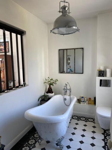 a white bath tub in a bathroom with a mirror at Maison du bonheur in Villiers-sur-Marne