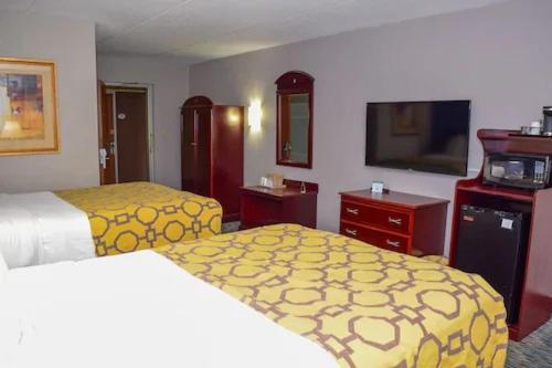 a hotel room with two beds and a flat screen tv at Baymont by Wyndham Michigan City in Michigan City