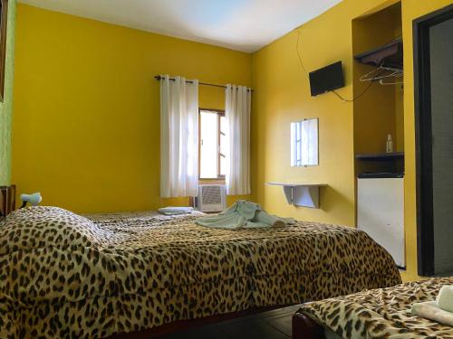 a room with two beds with yellow walls at Pousada Pratagy in Saquarema