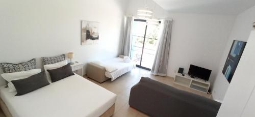 a white living room with a couch and a tv at APC Apartamento Palmela Village in Palmela