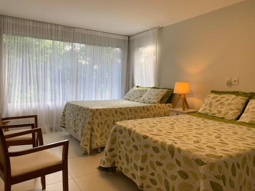 um quarto de hotel com duas camas e uma janela em Resort Villas do Pratagy em Maceió