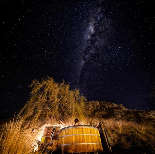 a man standing on a boat under a starry sky at Cottages at Kinross in Gibbston