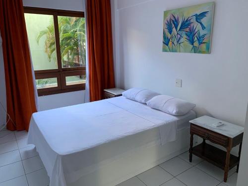 een slaapkamer met een wit bed en een raam bij Apartamento Porto Praia do Forte in Praia do Forte