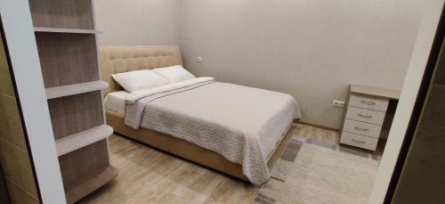 um pequeno quarto com uma cama e uma mesa de cabeceira em Сучасна квартира em Lutsʼk