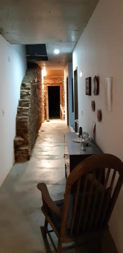 Cette chambre dispose d'une chaise et d'un mur en pierre. dans l'établissement Casa da Vila Santo Antônio - 3 suítes, à Piranhas
