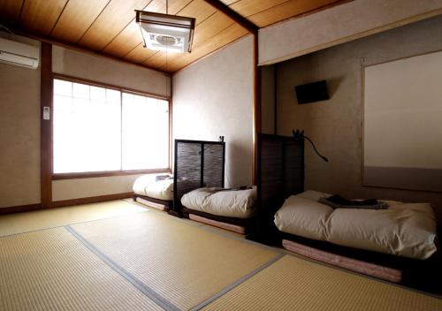 Izumo guesthouse itoan في إزومو: غرفة بثلاث اسرة ونافذة