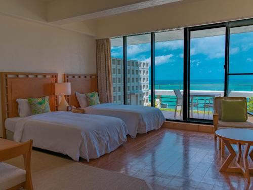 two beds in a hotel room with a view of the ocean at The Moon Beach Museum Resort in Onna