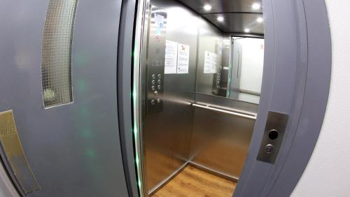 um elevador de metal com uma porta de vidro com piso de madeira em Sun Hotel em Bruxelas