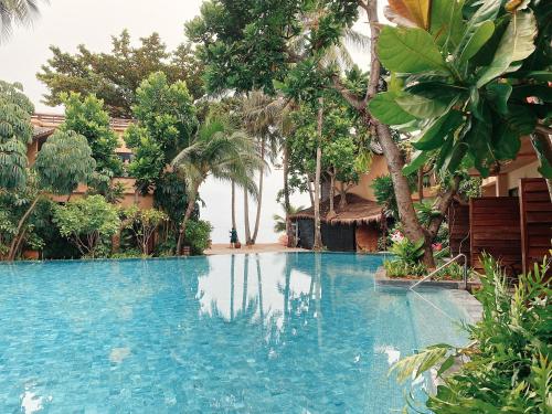 a swimming pool in a resort with palm trees at Buri Rasa Village Phangan in Thong Nai Pan Noi