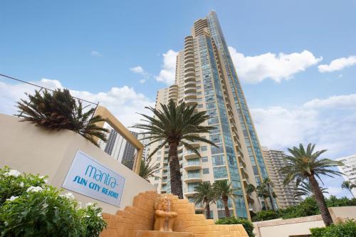a large building with palm trees in front of it at Mantra Sun City in Gold Coast