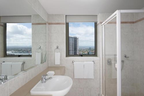 a bathroom with a sink and a shower with two windows at Mantra Sun City in Gold Coast
