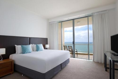 a bedroom with a large bed and a view of the ocean at Mantra Sun City in Gold Coast