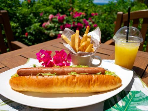 a plate with two hot dogs and french fries and a drink at The Moon Beach Museum Resort in Onna