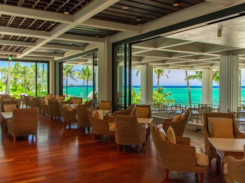 a restaurant with chairs and tables and a view of the ocean at The Moon Beach Museum Resort in Onna