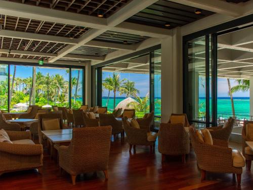 a restaurant with tables and chairs and a view of the ocean at The Moon Beach Museum Resort in Onna