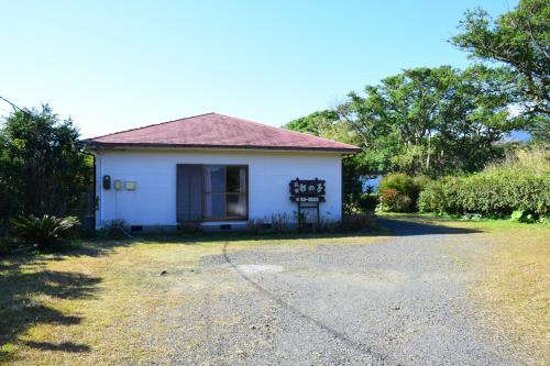 a small white house with a driveway at Yakushima Minsyuku Suginoko in Yakushima