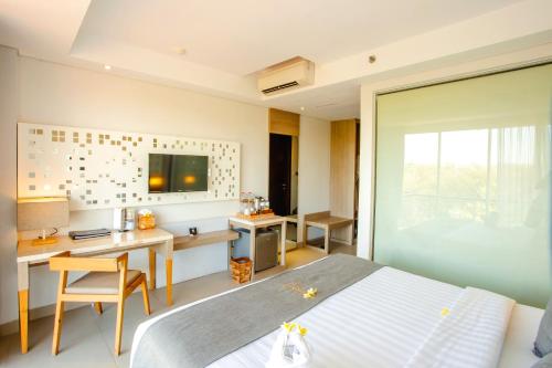 a bedroom with a bed and a desk and a table at Jimbaran Bay Beach Resort and Spa by Prabhu in Jimbaran