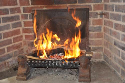 a brick fireplace with a fire in it at Gite Les Robins in Rebourseaux