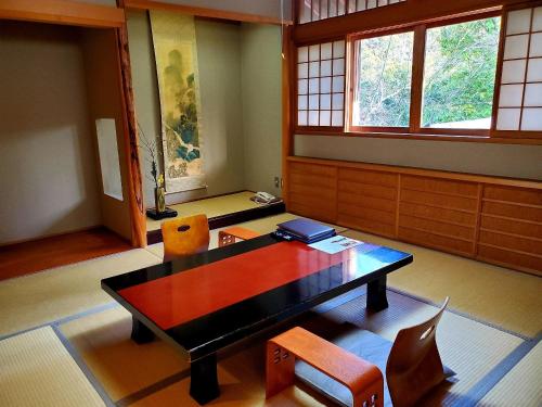 a room with a table and chairs and windows at Ryotei Tanokura in Yufuin