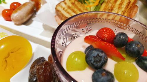 a bowl of yogurt with fruit and berries on a plate at Keret Accommodation in Bellville
