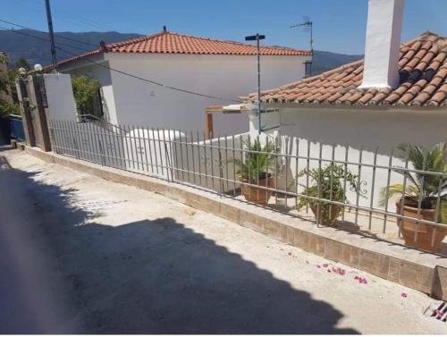 a white house with a fence and plants on a street at VERANDA BLUE - POROS in Poros