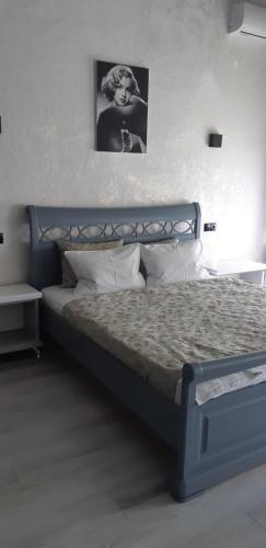 a bedroom with a blue bed with a black and white picture at Apartment on Soborna 91 in Vinnytsya