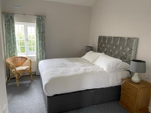 a bedroom with a bed and a chair and a window at The Granary in Saundersfoot