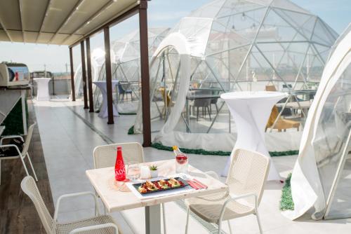 un tavolo con vassoio di cibo su un balcone con tende di Hotel Nevis Wellness & SPA a Oradea