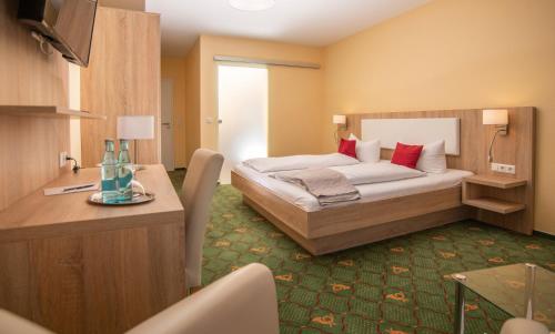a hotel room with a bed and a table at Hotel Garni Zur Alten Post in Lembruch