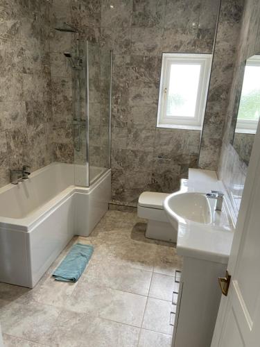 a bathroom with a tub and a sink and a toilet at The Granary in Saundersfoot